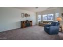 Spacious living room featuring a cozy fireplace, neutral carpet, and large windows at 5596 W Mercer Ln, Glendale, AZ 85304