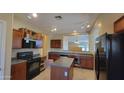 Open kitchen with island, wood cabinets and black appliances at 6908 S 54Th Ln, Laveen, AZ 85339