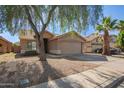 Traditional single-story home with a two-car garage, desert landscaping, and a mature shade tree in the front yard at 7310 N 68Th Ln, Glendale, AZ 85303