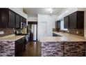 Modern kitchen boasting stainless steel appliances, granite countertops, and dark wood cabinets at 909 E Harwell Rd, Phoenix, AZ 85042