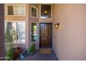 Inviting front entryway with wood door, sidelight windows, potted plants and warm exterior lighting at 1204 S Arroya Cir, Mesa, AZ 85206