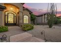 Inviting front entrance with a decorative iron door, lush landscaping, and stone accents at 1935 E Seminole Dr, Phoenix, AZ 85022