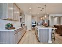 Bright kitchen with an island, light wood floors, pendant lights, and stainless steel appliances at 29408 N 224Th Dr, Wittmann, AZ 85361