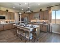 Modern kitchen boasts an island with seating, stainless steel appliances, and beautiful wood-look flooring at 37795 W Padilla St, Maricopa, AZ 85138