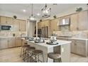 Bright kitchen features an island with seating, stainless steel appliances, and stylish pendant lighting at 37795 W Padilla St, Maricopa, AZ 85138