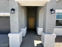 Inviting entryway with a covered porch, stylish light fixtures, and a view of the front door at 38105 W Bello Ln, Maricopa, AZ 85138