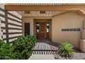 Inviting front entrance with wooden door, trellis, desert landscaping and decorative windows at 16927 E Trojan Ct, Fountain Hills, AZ 85268