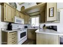 Cozy kitchen featuring light wood cabinets, white appliances, and ample counter space for meal preparation at 17200 W Bell Rd # 812, Surprise, AZ 85374