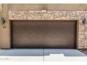 Attached two-car garage with a brown door and stone accents on a modern townhome at 2000 N 36Th St # 17, Phoenix, AZ 85008