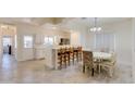 Bright dining area with bar seating, a white table with floral chairs, and modern gray-toned tile floors at 1409 E Apollo Rd, Phoenix, AZ 85042