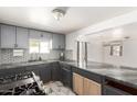 Well-lit kitchen featuring stylish gray cabinets, tile backsplash, and a convenient pass-through to the living area at 1916 W Tonto St, Phoenix, AZ 85009