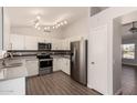Spacious kitchen with stainless steel appliances, white cabinets, and modern lighting fixtures above wood-look flooring at 19802 N 3Rd Ave, Phoenix, AZ 85027