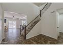 Grand foyer featuring a staircase with iron spindles and views into the living room and backyard at 40759 W Bravo Dr, Maricopa, AZ 85138