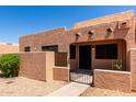 Inviting desert home featuring a stucco facade, secure gated entry, and shaded front porch with adobe accents at 8940 W Olive Ave # 59, Peoria, AZ 85345