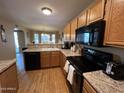 Well-lit kitchen featuring wooden cabinets, modern appliances, and hardwood floors at 19943 N 77Th Ave, Glendale, AZ 85308