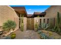 Stylish desert home entrance with rustic wooden gate, brick walls, and various cacti at 30600 N Pima Rd # 61, Scottsdale, AZ 85266