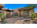 A stone-paved walkway leads to the modern desert home with a wooden gate and manicured succulents at 30600 N Pima Rd # 61, Scottsdale, AZ 85266