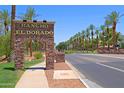 Attractive Rancho El Dorado community entrance with palm trees and landscaped median at 42812 W Venture Rd, Maricopa, AZ 85138