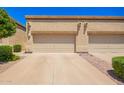 View of the garages and driveways of a row of houses with low shrubs under a clear blue sky at 6730 E Hermosa Vista Dr # 72, Mesa, AZ 85215