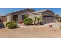 Tan home with two-car garage, desert landscaping, and security gate at 12132 W Caribbean Ln, El Mirage, AZ 85335