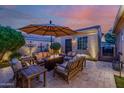 Cozy outdoor patio featuring cushioned seating and a warm fire pit under an umbrella at 13716 W Nogales Dr, Sun City West, AZ 85375