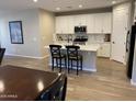 Bright kitchen featuring white cabinets, stainless steel appliances, and a functional island with barstool seating at 25657 N 185Th Dr, Surprise, AZ 85387