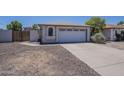 An exterior view shows the driveway and garage of a neutral toned one-story home at 3701 W Villa Maria Dr, Glendale, AZ 85308
