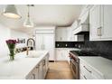 Modern kitchen featuring white cabinets, stainless steel appliances, an island with a sink, and a black backsplash at 4125 N 64Th St, Scottsdale, AZ 85251