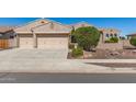 Charming home featuring a three car garage with neutral toned doors and desert landscaping in the front yard at 5107 N 194Th Dr, Litchfield Park, AZ 85340