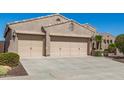 Charming home featuring a three car garage with neutral toned doors and desert landscaping in the front yard at 5107 N 194Th Dr, Litchfield Park, AZ 85340