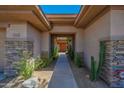 Inviting covered walkway leading to a stunning front door framed by desert plants and stone columns at 7283 E Brisa Dr, Scottsdale, AZ 85266