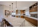 Modern kitchen with stainless steel appliances, wood cabinets, and a large marble island with seating at 8880 E Paraiso Dr # 120, Scottsdale, AZ 85255