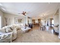 Bright and open living room with travertine floors, a modern ceiling fan, and views of the kitchen and dining areas at 8880 E Paraiso Dr # 120, Scottsdale, AZ 85255