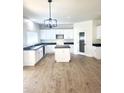 Bright kitchen with an island, white cabinets, modern lighting, and dark countertops at 2114 N 94Th Ave, Phoenix, AZ 85037