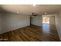 A bright living room with wood flooring, a ceiling fan, and an open kitchen in the background at 5951 W Granada Rd, Phoenix, AZ 85035