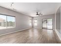 Spacious living room featuring wood-look floors, large windows, a ceiling fan, and sliding glass doors to the patio at 1102 N 5Th St, Buckeye, AZ 85326