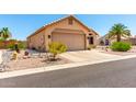 Side view of a tan home featuring a two-car garage and desert landscaping at 11631 W Lemon Ct, Surprise, AZ 85378