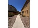 Exterior walkway alongside a property, featuring rock landscaping between homes at 1350 S Greenfield Rd # 1221, Mesa, AZ 85206