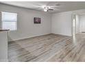 Open-concept living room featuring sleek wood-look flooring, a bright window, and freshly painted white walls at 20410 N Mac Neil St, Maricopa, AZ 85138