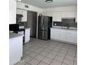 Bright kitchen with stainless steel appliances, white cabinets, and tile flooring at 4316 W Rose Ln, Glendale, AZ 85301