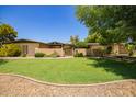Lovely home with a lush green lawn, decorative gate, and desert landscaping at 6330 E Delcoa Ave, Scottsdale, AZ 85254