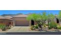 Desert home with a two-car garage and drought-resistant landscaping, including cacti and native plants at 6714 E Nightingale Cir, Scottsdale, AZ 85266