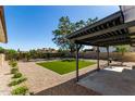 Backyard featuring gravel, artificial turf, mature landscaping, and a covered patio at 1521 W Jacinto Ave, Mesa, AZ 85202