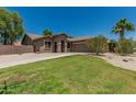 Beige single-story home featuring desert landscaping, green lawn and a two-car garage at 162 W Raven Dr, Chandler, AZ 85286