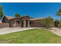 Beige single-story home featuring desert landscaping, green lawn and a two-car garage at 162 W Raven Dr, Chandler, AZ 85286