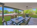 Covered backyard patio with an outdoor dining area and view of the pool and lush greenery at 2607 E Mercer Ln, Phoenix, AZ 85028