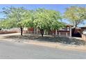 Quaint brick home with a white picket fence, surrounded by mature shade trees and a well-maintained yard at 3006 W Stella Ln, Phoenix, AZ 85017