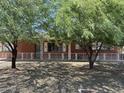 Brick house with decorative white fence and mature trees offering shade and curb appeal at 3006 W Stella Ln, Phoenix, AZ 85017