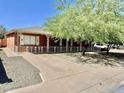 Classic brick home with charming white shutters and decorative fence, set back from the street with a long driveway at 3006 W Stella Ln, Phoenix, AZ 85017