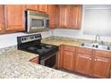 Well-lit kitchen featuring an electric stovetop, stainless steel microwave, and granite countertops at 3420 W Danbury Dr # C130, Phoenix, AZ 85053